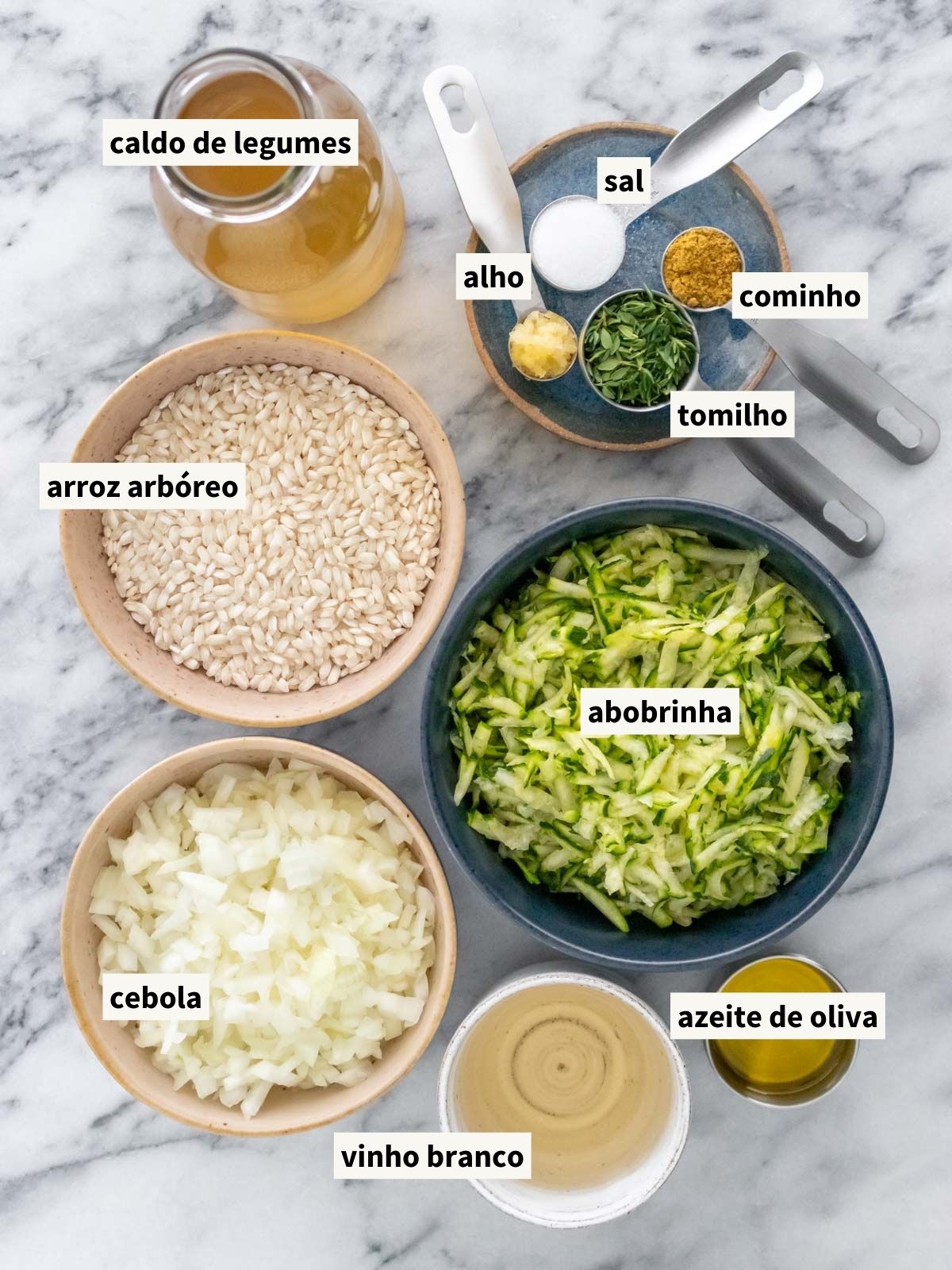 ingredientes para fazer risoto de abobrinha com tomilho, incluindo caldo de legumes caseiro, azeite de oliva, cebola picada, cominho em pó, sal, tomilho fresco, alho picado, arroz arbóreo, vinho branco, abobrinha ralada