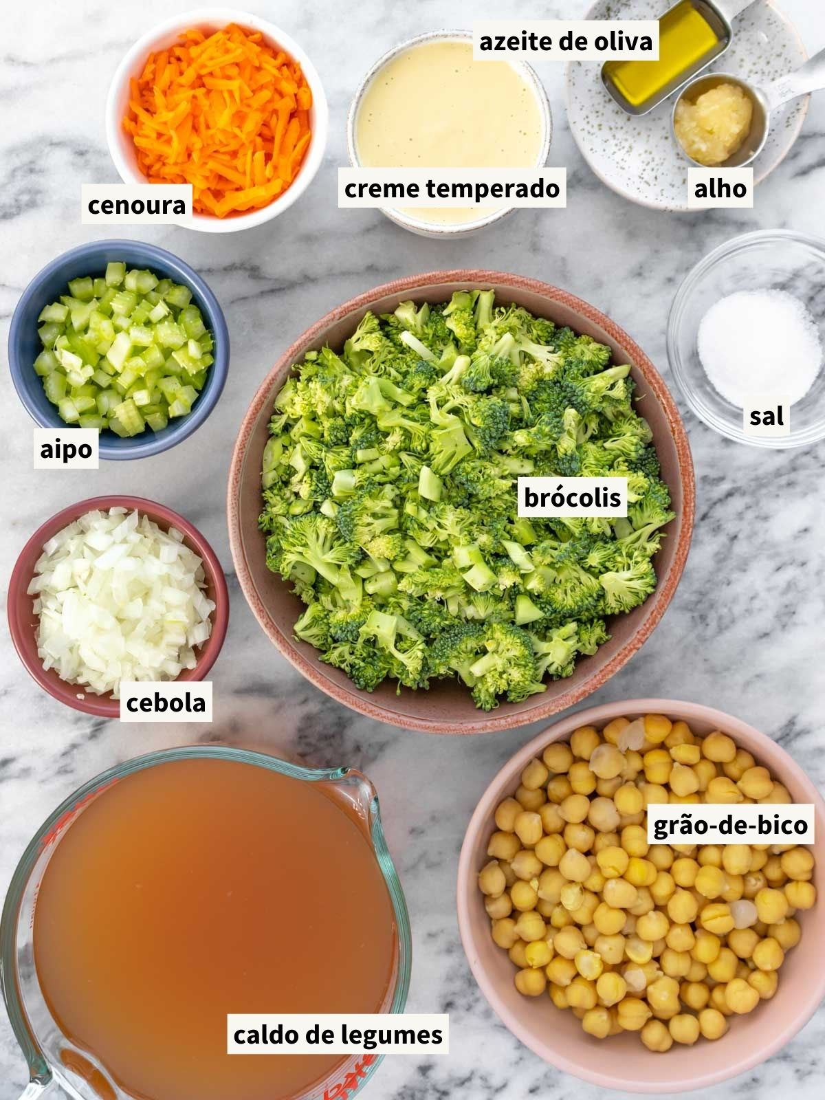 ingredientes para fazer sopa de brócolis cremosa, incluindo azeite de oliva, cebola, sal, talo de aipo (salsão), cenoura, alho, caldo de legumes, brócolis, grão-de-bico cozido, pimenta-do-reino moída e creme de castanha-de-caju temperado