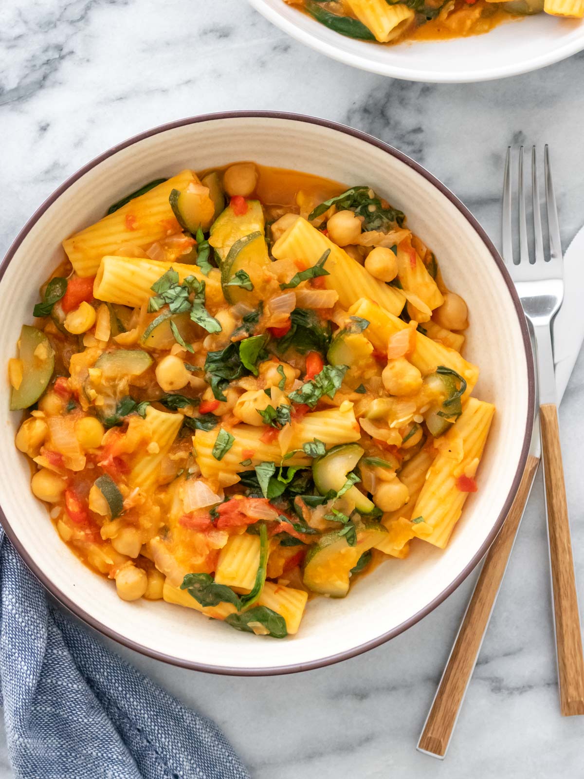macarrão com vegetais e molho vermelho servido em um prato com manjericão fresco picado