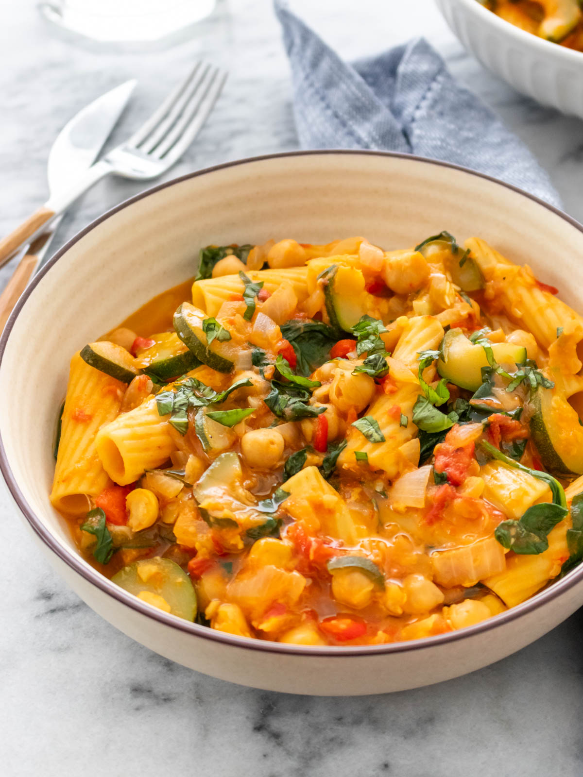 macarrão com vegetais e molho vermelho servido em um prato com manjericão fresco picado