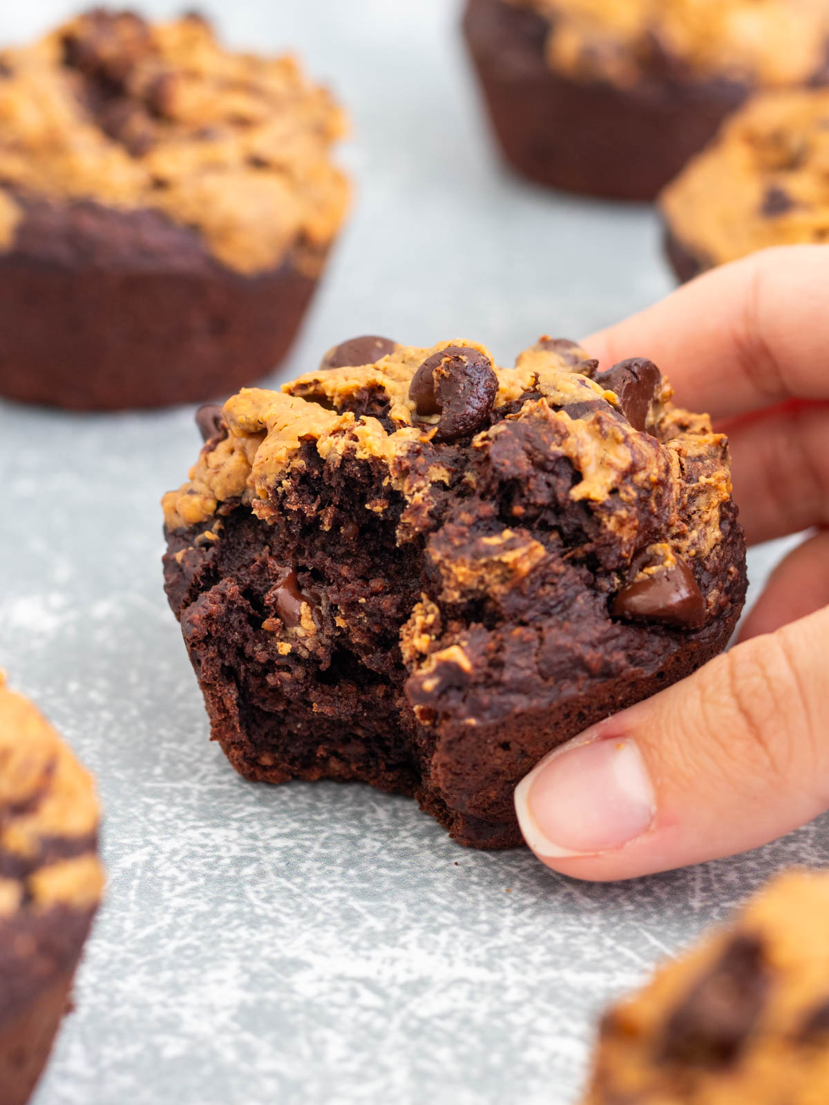 muffin de chocolate e banana com cobertura de pasta de amendoim, com uma mordida mostrando sua textura macia e fofinha