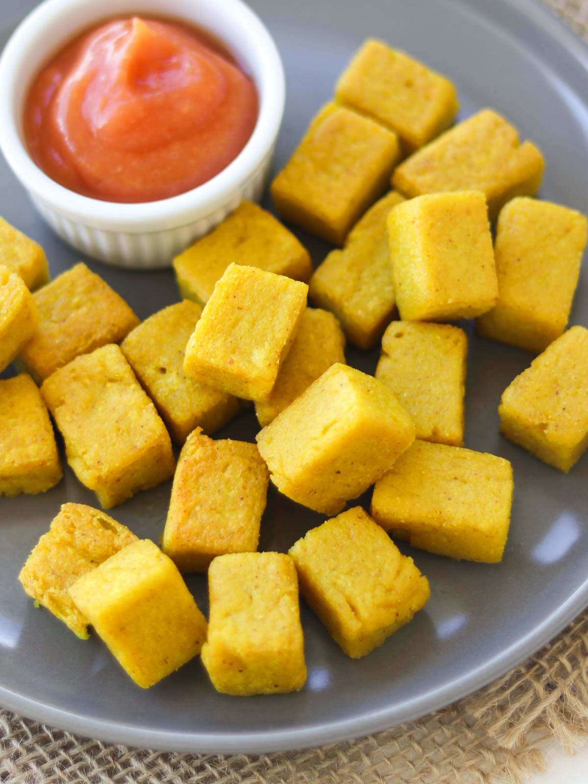 cubinhos de tofu de grão-de-bico frito servido em um prato com ketchup