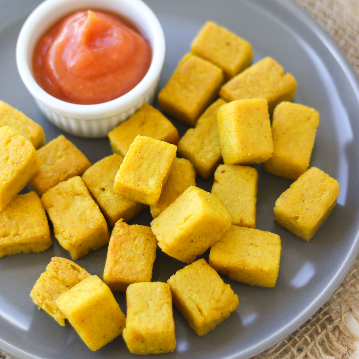 cubinhos de tofu de grão-de-bico frito servido em um prato com ketchup
