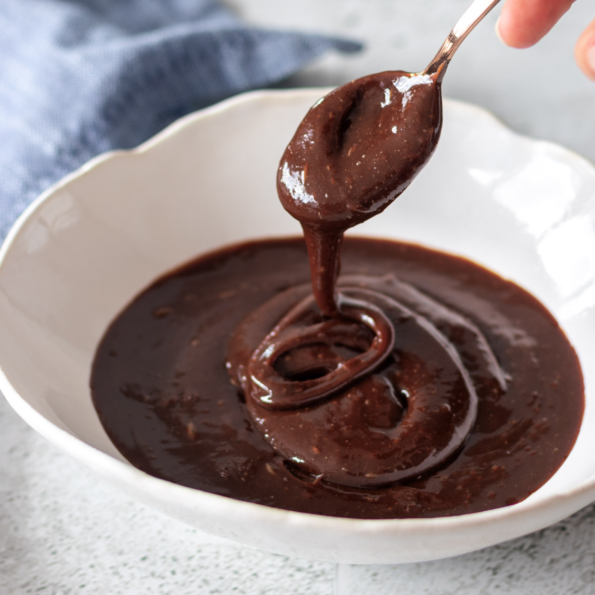 colher sendo retirado de tigela de brigadeiro vegano, mostrando sua textura cremosa