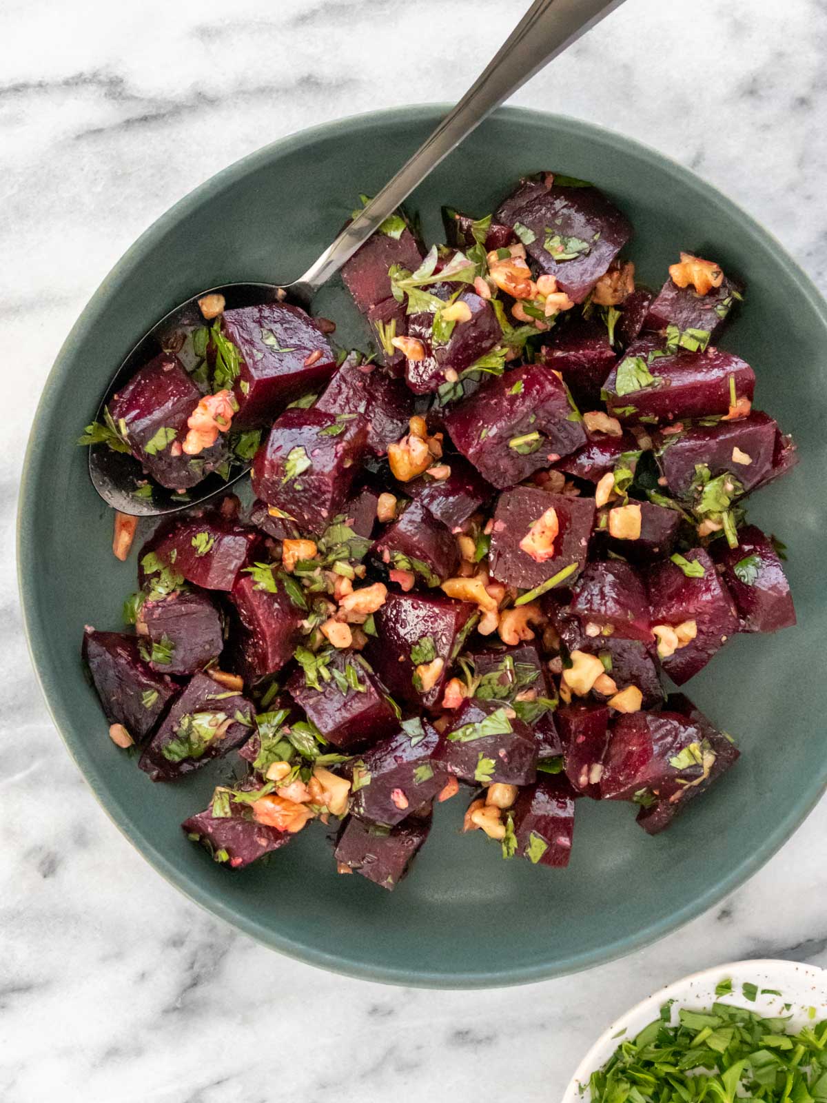 salada de beterraba cozida com molho de limão, salsinha e nozes picadas em um prato de servir